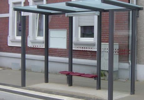 Eine graue dreifeldrige Wartehalle mit Sitzbank und Beleuchtung