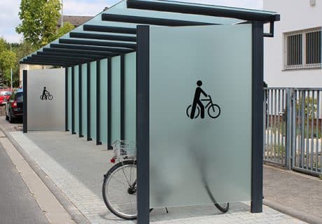 Eine Fahrradüberdachung am Straßenrand mit undurchsichtigen Scheiben
