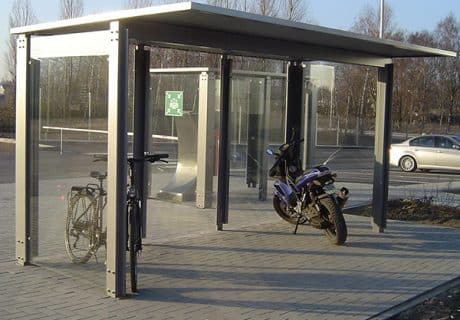 Eine Fahrradüberdachung am Straßenrand mit je einem Fahrrad und Motorrad
