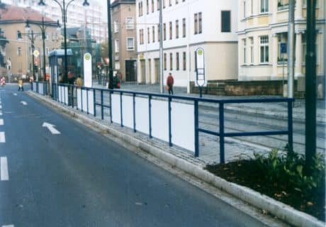 Eine Geländerreihe am Straßenrand mit Handlauf und Spritzschutz