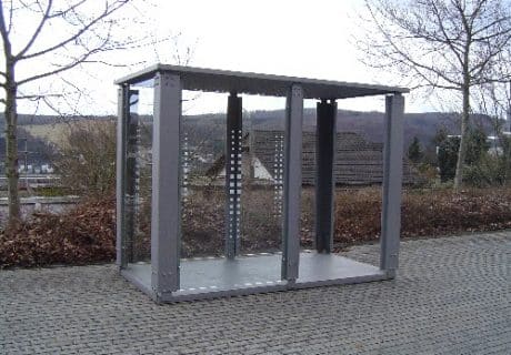 Eine graue Wartehalle mit Bodenplatte am Wegesrand