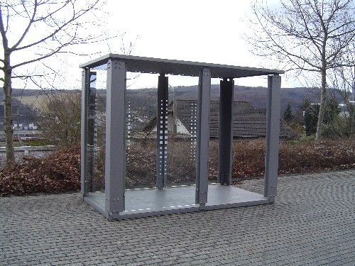 Ein Raucherunterstand aus Stahl mit Bodenplatte am Wegesrand