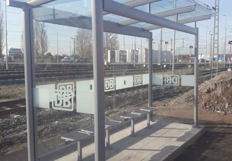 Eine graue dreifeldrige Wartehalle mit Betonbodenplatte und Drahtgittersitzbänken