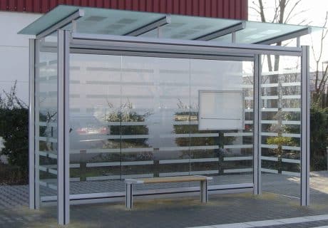 Eine graue dreifeldrige Wartehalle mit Holzsitzbank