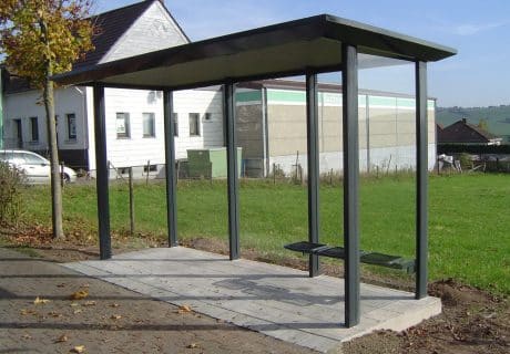 Eine graue dreifeldrige Wartehalle einschließlich Betonbodenplatte und Plattendekor-Oberfläche