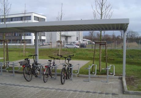 Eine Fahrradüberdachung mit mehreren Fahrradbügeln am Wegesrand