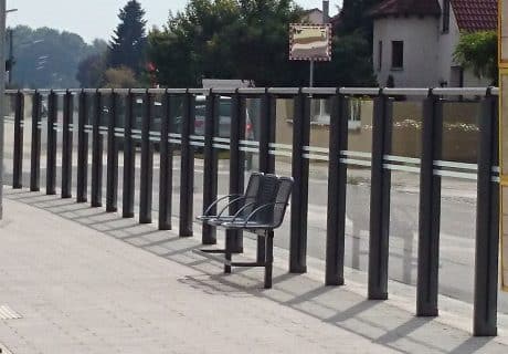 Eine Geländerreihe am Straßenrand mit drei Drahtgittersitzen