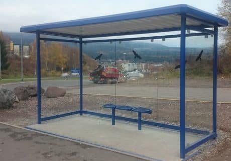 Eine blaue Wartehalle mit Scheibendekor am Wegesrand