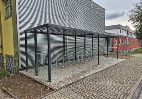 Eine Fahrradüberdachung mit mehreren Fahrradbügeln vor einer Metallwand