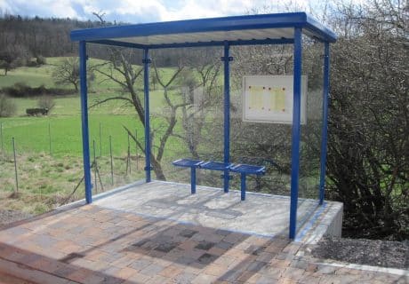 Ein blauer Raucherunterstand mit Bodenplatte am Wegesrand