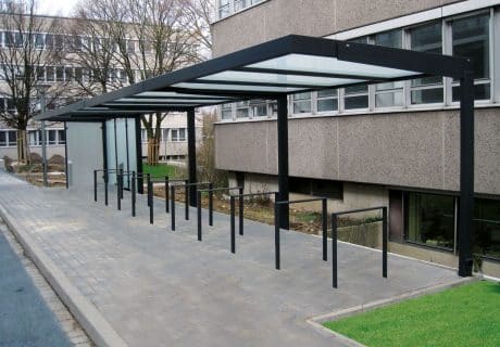 Eine Fahrradüberdachung mit mehreren Fahrradbügeln vor einem Gebäude