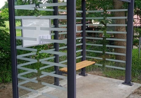 Eine graue zweifeldrige Wartehalle am Wegesrand