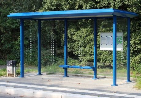 Eine blaue Wartehalle mit Gründach am Straßenrand