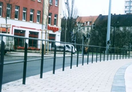 Eine Geländerreihe am Straßenrand mit Handlauf und Knieholm
