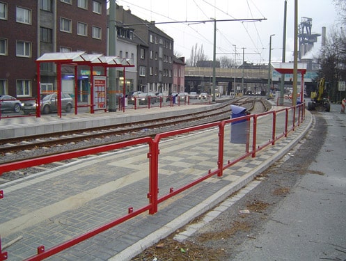 Eine rote Geländerreihe mit undurchsichtigen Scheiben am Straßenrand