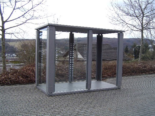 Ein Raucherunterstand aus Stahl mit Bodenplatte am Wegesrand