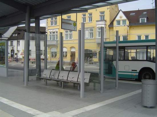 Ein Windschutz an einem Bahnhof, der mehrere Metallsitze umschließt
