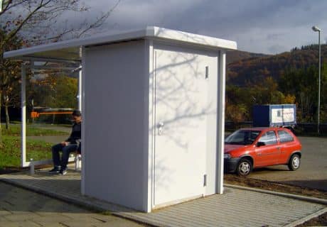 Eine Person sitzt in einer Wartehalle am Wegesrand