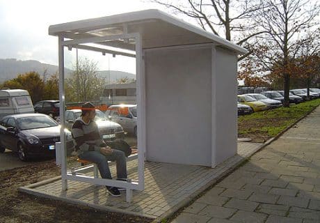 Eine Person sitzt in einer Wartehalle am Wegesrand