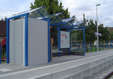 Eine blaugraue Wartehalle mit Personaltoilette am Bahnsteig
