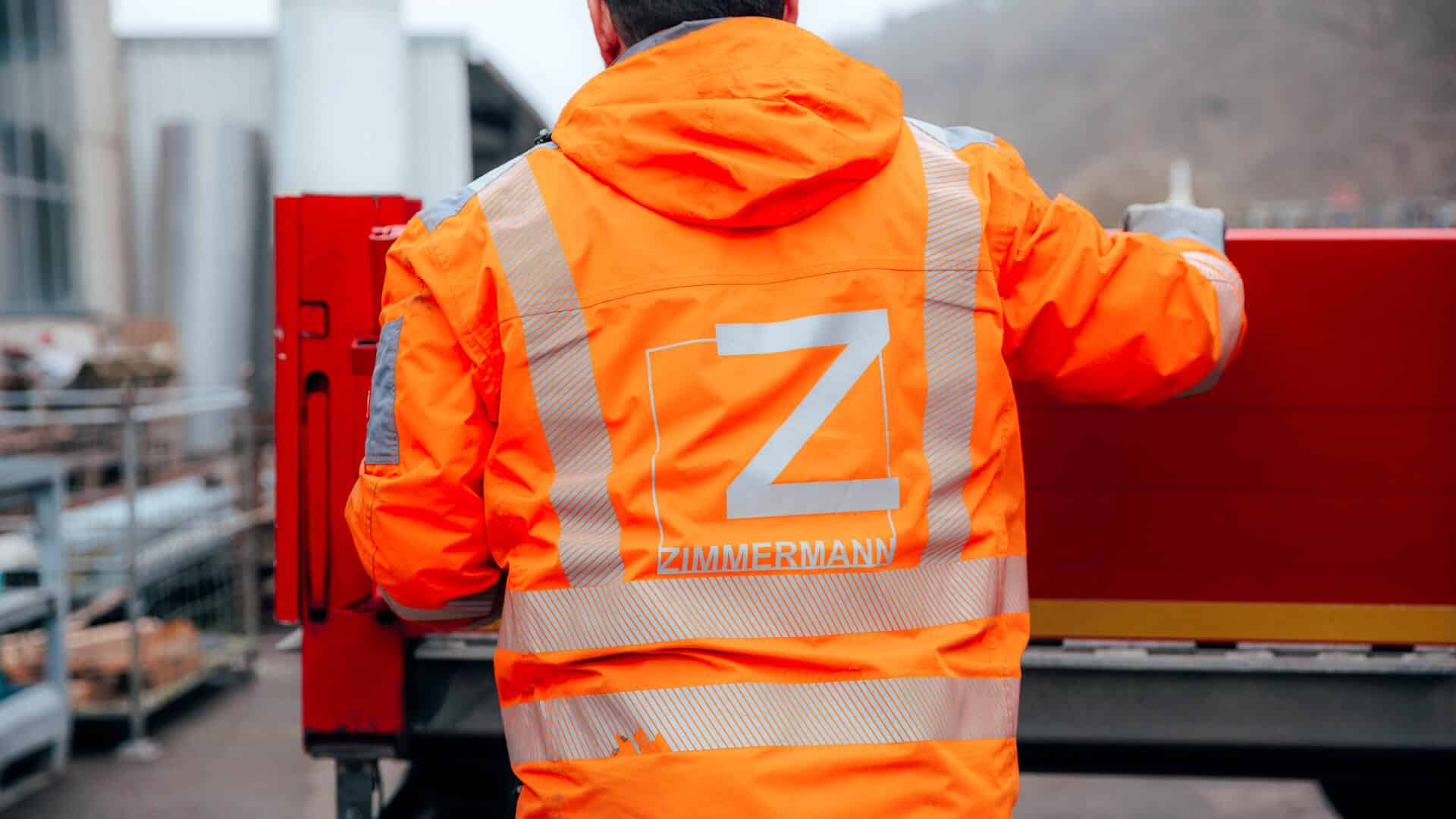Mitarbeiter mit orangener Warnweste auf der das Logo von Zimmermann Stadtmöblierung zu sehen ist